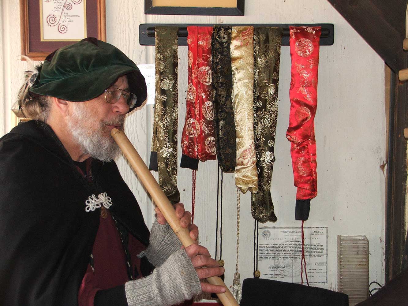 Rod playing a shakuhachi in front of the display of decorative bags